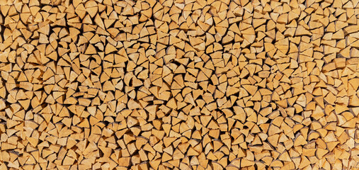 Großer Feuerholz Holzstoß aus vielen kleinen, ordentlich gestapelten braunen Holzscheiten