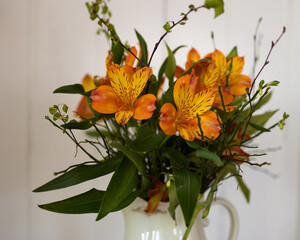 A spring bouquet with birch leaves, Alstromeria and blueberry rice in an antique jug with white background