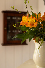 A spring bouquet with birch leaves, Alstromeria and blueberry rice in an antique jug with a dark key cabinet behind