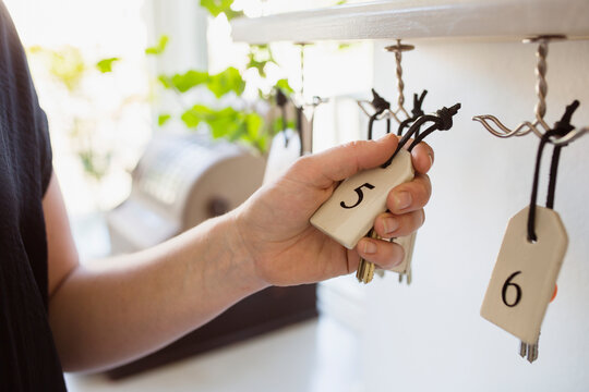 Hand reaching for hotel room key hanging on hook