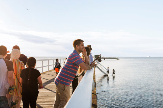 Smiling man standing on pier and looking at sea