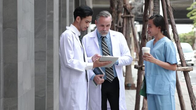 Slow motion VDO Professional medical staff people successful and teamwork concept. Diverse doctor and nurse meeting on teblet together at hospital medical wellness center. Drink coffee outdoor