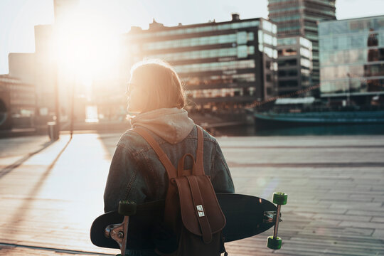 Woman in street carrying skateboard
