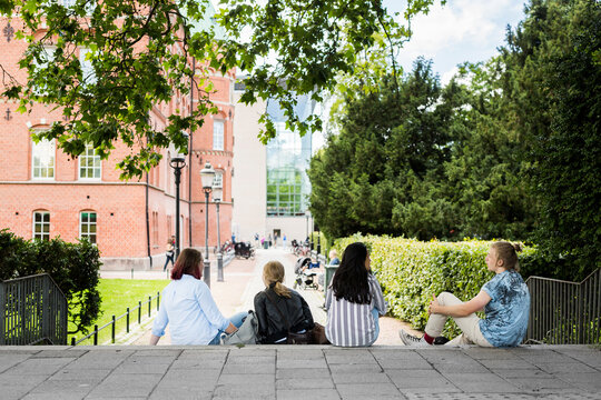 Students sitting on stairs outside library during study session.