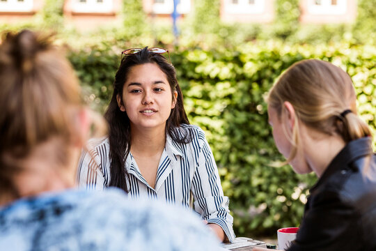 Students meeting up for study session at sidewalk cafe outside library.