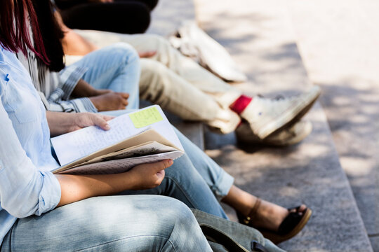 Students sitting on stairs outside library during study session.