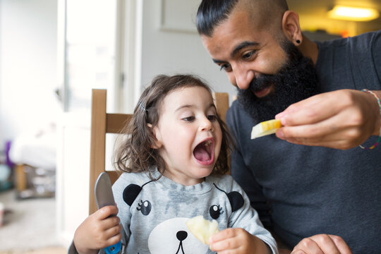 Step father feeding his little daughter at table