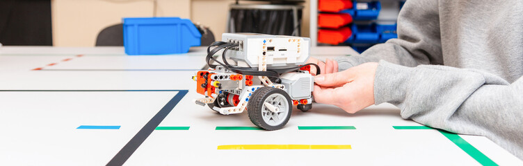 Teen student with diy robot on stem education class.Fixing mechanic toy car.Teen scientist working on new project.Stem education Learning To Program Robot Vehicle.Banner.