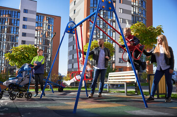 Happy family - father, mother and children having fun together at modern courtyard of city...