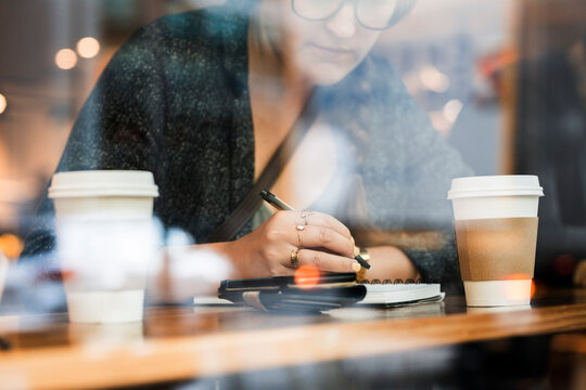 Young woman in cafeteria writing in notebook