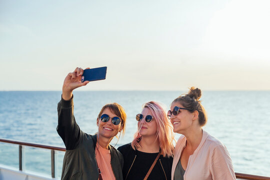 Three women taking selfie on ship deck