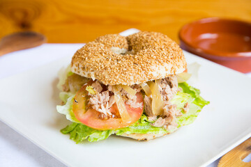Delicious tuna sandwich on bagel bread. A bagel is a bread traditionally made from wheat flour and usually has a hole in the center.