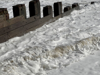 Natural unpolluted sea foam made by air and sand compression in a rising tide