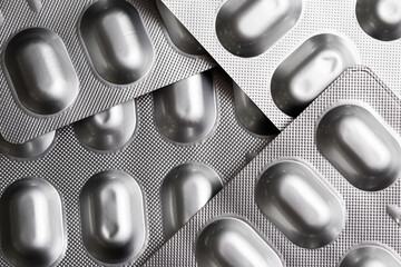 Silver pill blister. Silver medicine container. Metal drug blister with medicine capsules. Pharmacy background. Simple illness curing texture. Aluminum usage in industry.	