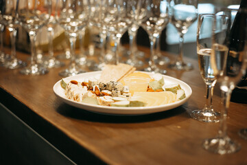 lots of champagne glasses and a plate of cheese on the wooden bar counter
