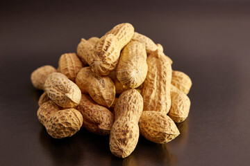 A pile of unshelled peanuts on a black background. An ingredient for preparing tasty and healthy dishes.