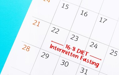 Calendar with schedule written INTERMITTEN FASTING, eating plan that switches between fasting and eating on regular schedule, eat only for a set of time