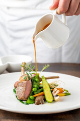 Chef pouring sauce on lamb chops with various vegetables at a fine dining restaurant © yalcinsonat