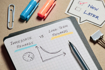 Immediate rewards vs Long-term rewards handwritten notes with graph on notebook. Hyperbolic discounting concept, selective focus.