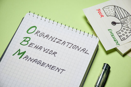 Organizational Behavior Management (OBM) handwritten on notepad with performance indicator on desk. A scientific approach to improve your business concept, selective focus.