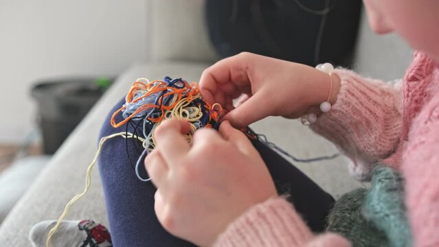 Cute Creative Caucasian Girl Trying to Untangle Hank Skein of Yarn
