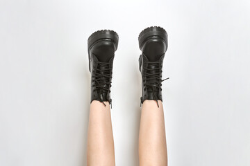 Woman legs in black combat boots on high heel platform with lug soles upside down, isolated white...