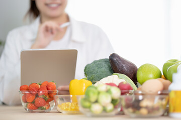 Close up hand of professional nutrition healthful surrounded by a variety of fresh fruits and...