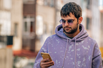 portrait of young man with sunglasses and mobile phone outdoors