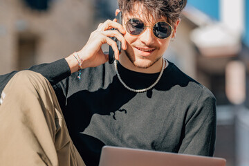 young man with mobile phone and laptop on outdoor terrace
