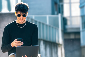 young man in the street with laptop and mobile phone