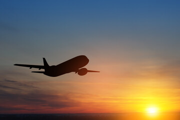Airplane taking off at the sunset sky. Silhouette of aircraft in the sky.