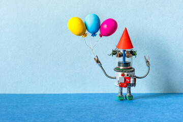 A festive greeting card for any event or birthday party. A happy robot in a paper red hat holds yellow blue violet balloons. Happy birthday poster template