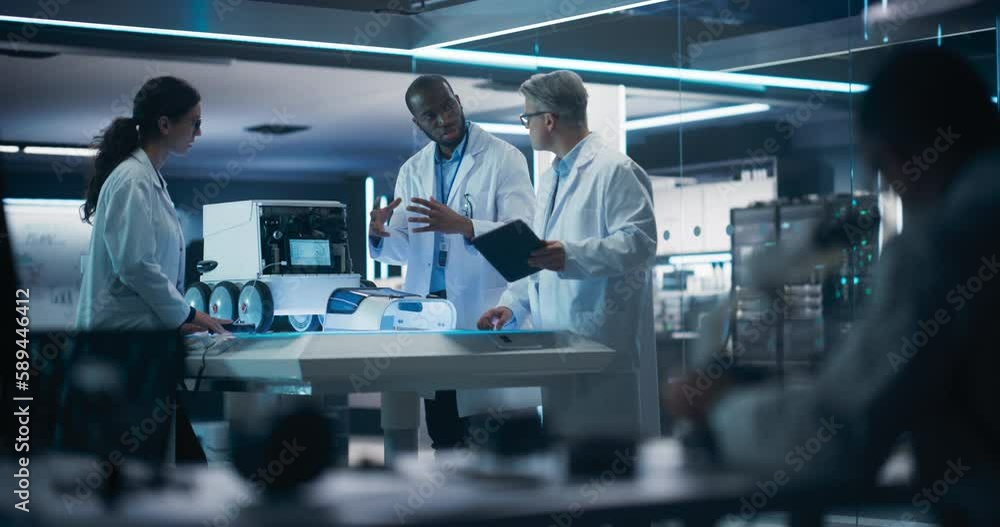 Fototapete Scientist Using a Modern Digital Microscope in a Research and Development Facility. Focus Switching to a Diverse Team of Industrial Specialists Working on Remotely Controlled Mobility Robot
