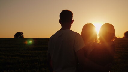 Fototapeta premium Young family with a child looking at a beautiful sunset