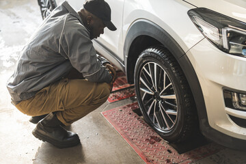 a mechanic looking at a wheel and checking its geometry at the car repair shop, full shot. High quality photo