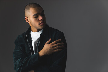 Young African American man with buzz cut on a dark studio background with dimmed lights. High...