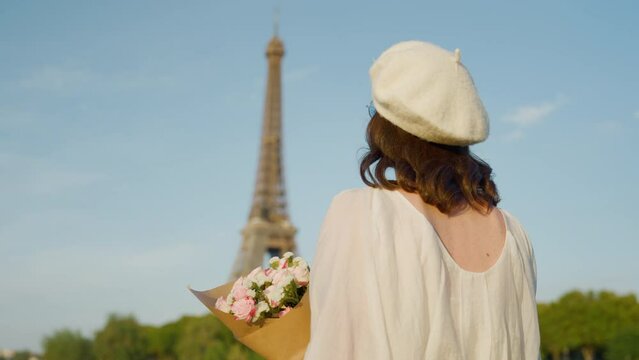 Beautiful girl with a bouquet of flowers on the bridge near the Eiffel Tower