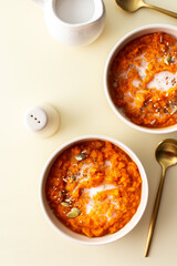 Healthy lunches, delicious pumpkin cream soup on yellow background, soup with sunflower and pumpkin seeds, sesame and flax and with coconut milk, top view