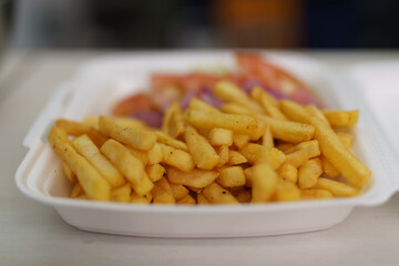 Styrofoam container with French fries and vegetables. Lunch box prepared for take away in a fast...