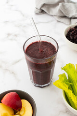 Healthy breakfast, frozen blueberry, avocado and banana smoothie, pea protein and flax seeds, lettuce and celery, apple, smoothie in a glass with a straw