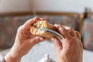 Alte Frau Oma Rentnerin sitzt am gedeckten Frühstückstisch beim Frühstück und isst ein mit Euro...