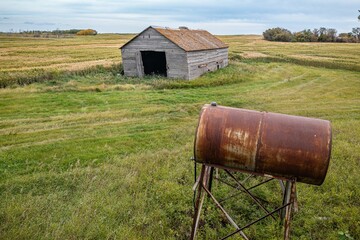 Aerial of an old abandoned wooden homestead and a rusty water tank in Canadian prairies