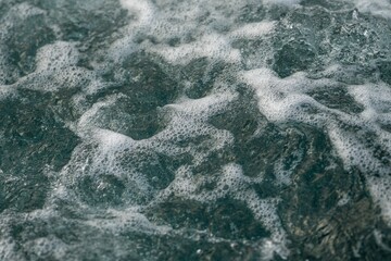 Fototapeta na wymiar Closeup view of white foamy waves on a turquoise body of water