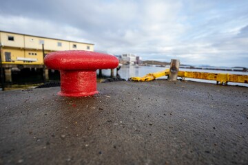 Red steel bollard at the harbor with a sea view in the background