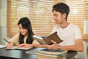 Male tutor giving private educational lesson to teenage asian girl. Homeschooling and education concept