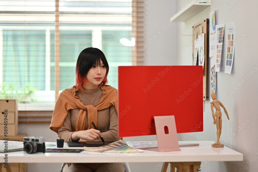 Poster beautiful young female designer using graphics tablet and working with color swatch samples at creat