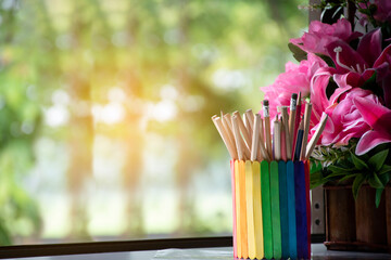 Closeup view of rainbow case which has various pencils inside, blurred nature ouside window background, concept for LGBT celebration in pride month and home decoration of LGBT people around the world.