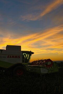 Claas harvester in the field harvesting sunflowers during sunset