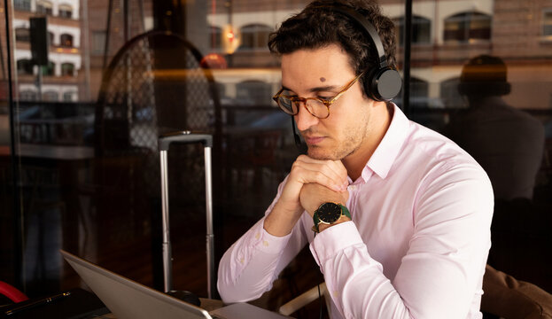 man with glasses resting his elbows on the table in front of the computer