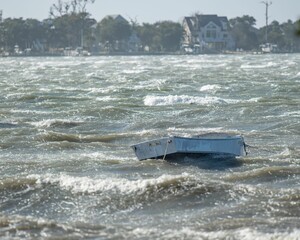 Small Wooden Rowing Boat on the shallow water of rough sea waves © Brian Horsley/Wirestock Creators